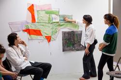 A person touches an artwork while three other people look at the artwork in a Memorial Hall painting studio