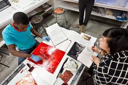 Two students working on print artworks at a table in Benson Hall. 