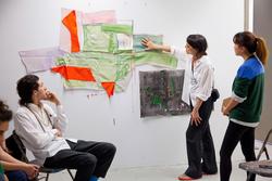 A person touches an artwork while three other people look at the artwork in a Memorial Hall painting studio