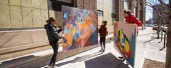 Three people carrying art pieces down North Main Street in Providence, Rhode Island