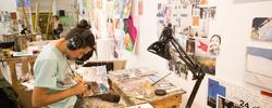 Person painting at a desk in a Memorial Hall studio.