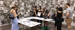 A group of people gather around a Graphic Design display at RISD's Grad Show.