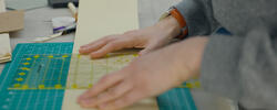 close up shot of someone measuring a piece of paper on top of a cutting mat