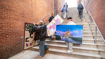 students on stairwell by risd museum holding large pieces of work