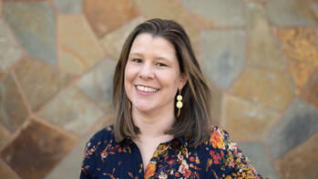 woman smiling in front of a stone wall