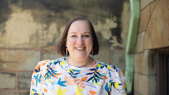 photo of a woman smiling outside infront of a stone wall