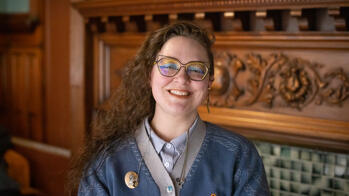photo of a person with glasses and rainbow makeup smiling