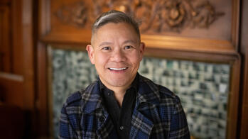 photo of a man smiling in front of a fireplace
