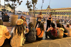 students and others gather outdoors around dusk in Mexico City