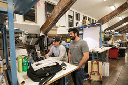 two Architecture grad students laugh while looking at computer screen together