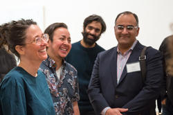 four people stand together laughing while at a social event