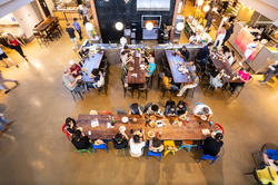 bird's eye view of people sitting at several long tables inside a dining hall