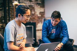 a student and an internship advisor talk while looking at a laptop screen