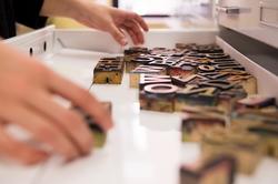 A person reaching their hands into a drawer filled with type letters for Graphic Design