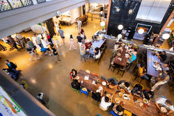 a bird's-eye view of people sitting at several long tables inside a dining hall