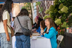 students talking to a staff member at a table outside