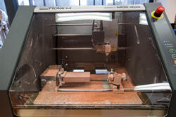 closeup of the inside of a 3d milling machine at work, with sawdust on the inside surface