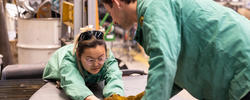 Two people in green safety jackets work over a platform