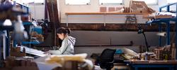 Student in a gray hoodie working at a desk in an architecture studio