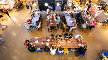 bird's eye view of people sitting at several long tables inside a dining hall