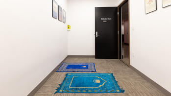 photo of a reflection room, a small room with prayer mats and a door that says reflection room