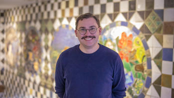photo of a person smiling infront of a mural