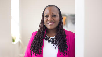 photo of a woman smiling with a white shirt and pink blazer