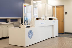 a white desk with glass front shields inside a medical office with a light blue wall behind it