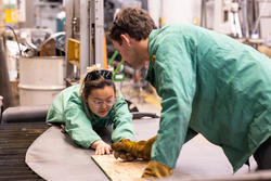 Two people in green safety jackets work over a platform