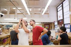 Two people examine a piece of metalwork in the Metcalf furniture studio.