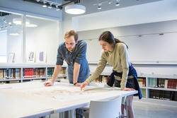 Two people are reviewing work together at a table in the RISD museum