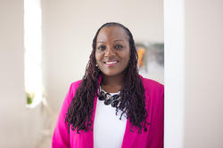 photo of a woman smiling with a white shirt and pink blazer